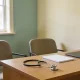 A calm GP consultation room in Australia with two chairs beside a desk near a window and a stethoscope resting on the desk in natural daylight.