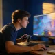 A game developer testing a video game at a desk in a home office in late afternoon light.