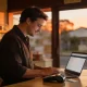 Small-business owner behind a shop counter looking at a website on a laptop.