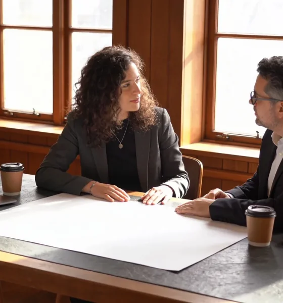 A small business owner and an accountant reviewing blank reports together at a sunlit desk.