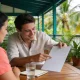 Migration agent consultation on a shaded office verandah in Darwin, two people at a wooden table among potted palms.