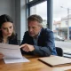 Person reviewing paperwork at a table in natural light outside a cafe on a Geelong street