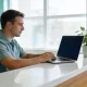 A dental practice owner working on a laptop at the reception desk of a bright modern clinic.