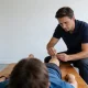 Physiotherapist performing dry needling on the calf of a patient lying face-down on a treatment table in a bright, calm Australian physiotherapy clinic