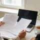 A taxpayer and an accountant reviewing tax paperwork together at a bright desk.