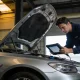 Mechanic in a Melbourne workshop using a diagnostic tablet on an open-bonnet silver European sedan