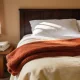 layered fleece and cotton bedding on a bed in a bright bedroom