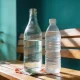 glass and plastic water bottles side by side on a timber bench