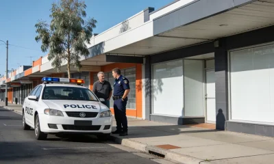 Security guard talking with a shop owner beside an unmarked white patrol car outside a Geelong shopfront