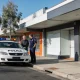 Security guard talking with a shop owner beside an unmarked white patrol car outside a Geelong shopfront