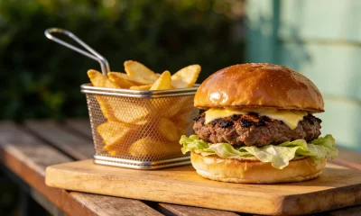 Handmade beef burger with a charred crust patty, melted cheese and fresh lettuce on a wooden board at a casual Australian cafe