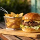 Handmade beef burger with a charred crust patty, melted cheese and fresh lettuce on a wooden board at a casual Australian cafe