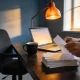 Person sorting paper receipts into piles at a home-office desk beside an open laptop in late-afternoon Australian light