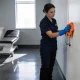 cleaner wiping a door handle in a bright medical clinic