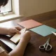 child folding origami with scissors and paper at a wooden table