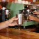 Customer at a local cafe counter holding out a plain stainless reusable coffee cup to the barista.