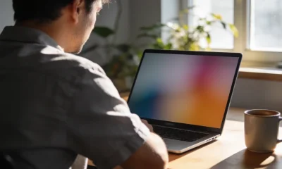 A small business owner studying analytics charts on a laptop at a sunlit desk.