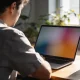 A small business owner studying analytics charts on a laptop at a sunlit desk.