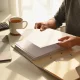 A person sorting blank papers into folders at a tidy home office desk in natural light.