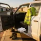 White work utility vehicle parked on a suburban Laverton street, driver door open, high-vis vest, blank logbook and papers on the seat.