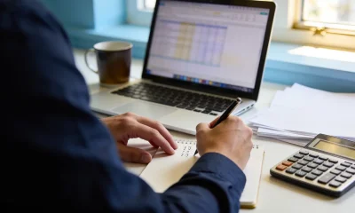 Person reviewing tax papers and figures with a calculator at a tidy home-office desk in the morning.