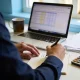 Person reviewing tax papers and figures with a calculator at a tidy home-office desk in the morning.